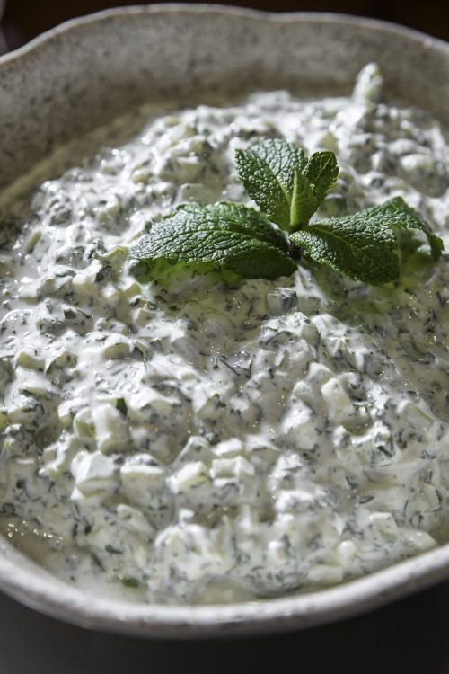 Sauce crémeuse au yaourt avec concombre et herbes, décorée d’une feuille de menthe.