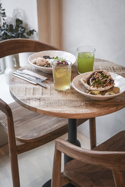 Table Dip Honest Food avec deux assiettes méditerranéennes et boissons fraîches servies sur une table en bois.