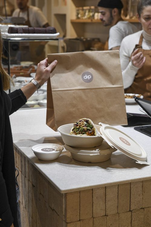 Commande à emporter Dip Honest Food avec sac kraft Dip et bowls prêts à emporter au comptoir.